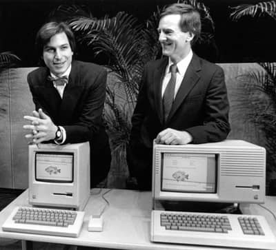6 Feb 1984 - Steve Jobs poses with Macintosh while Sculley rests on a LISA